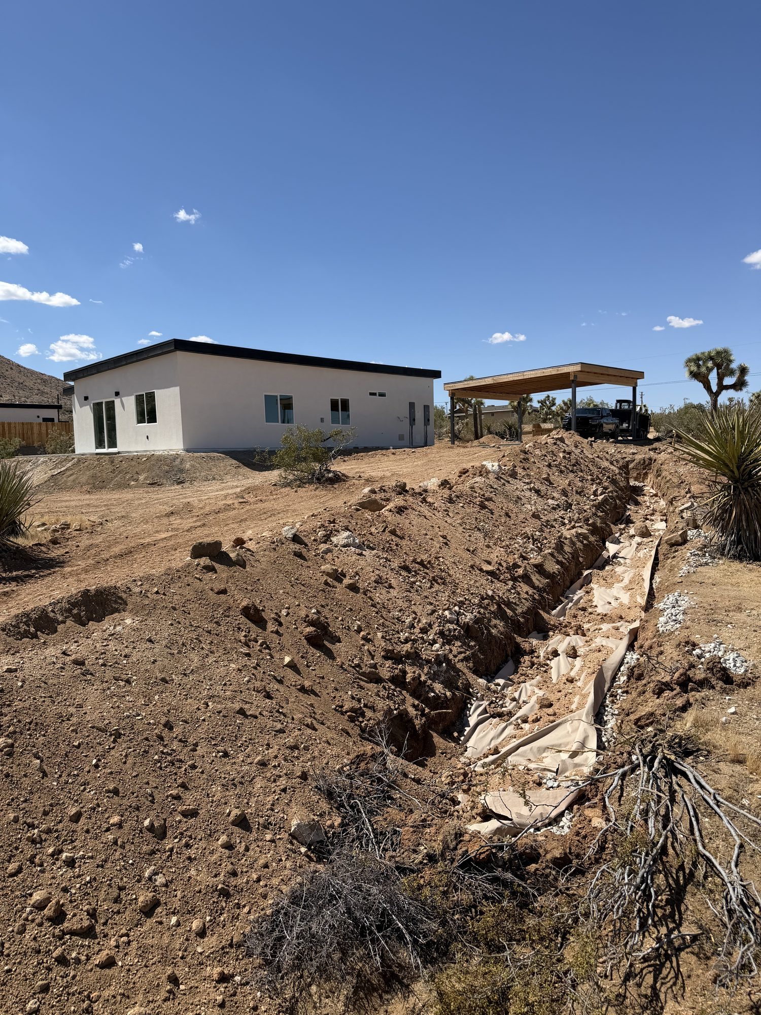 Open septic trench with spoil piled alongside a house