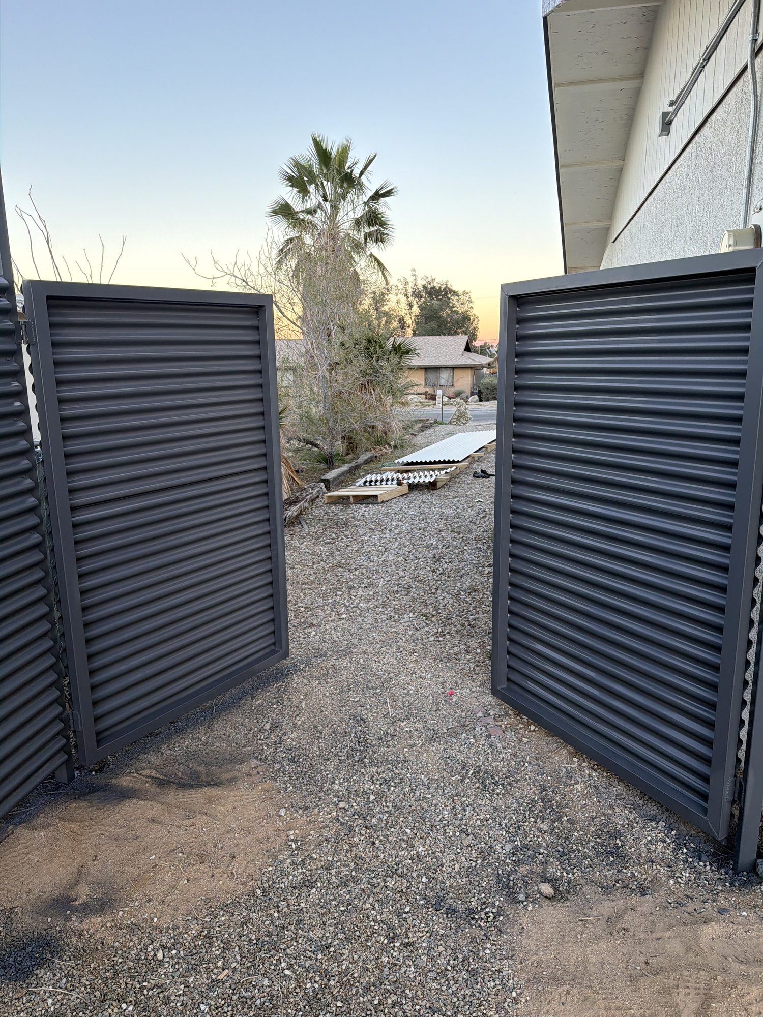 Dark louvered metal privacy gates installed at a desert property