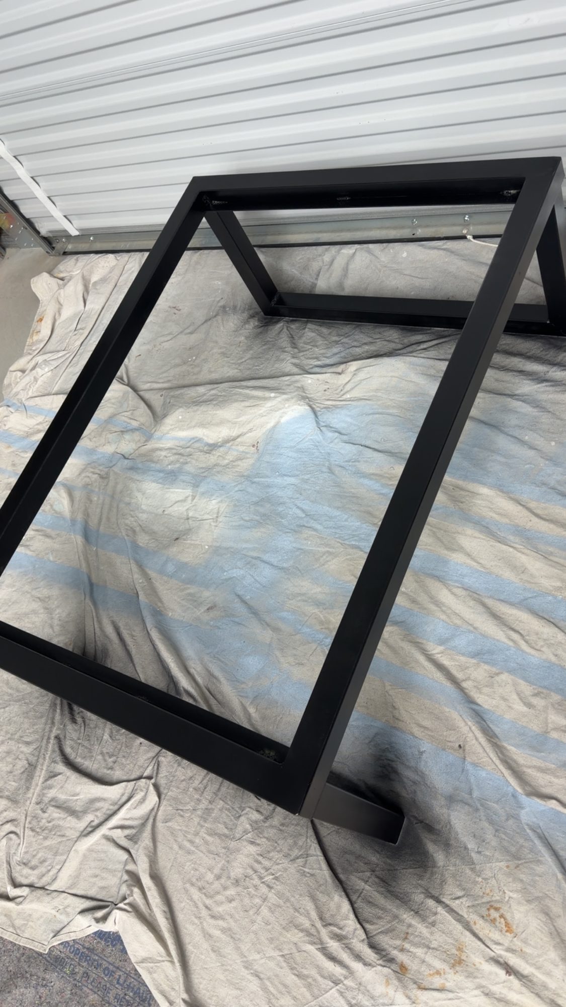 Black steel table base frame on a drop cloth