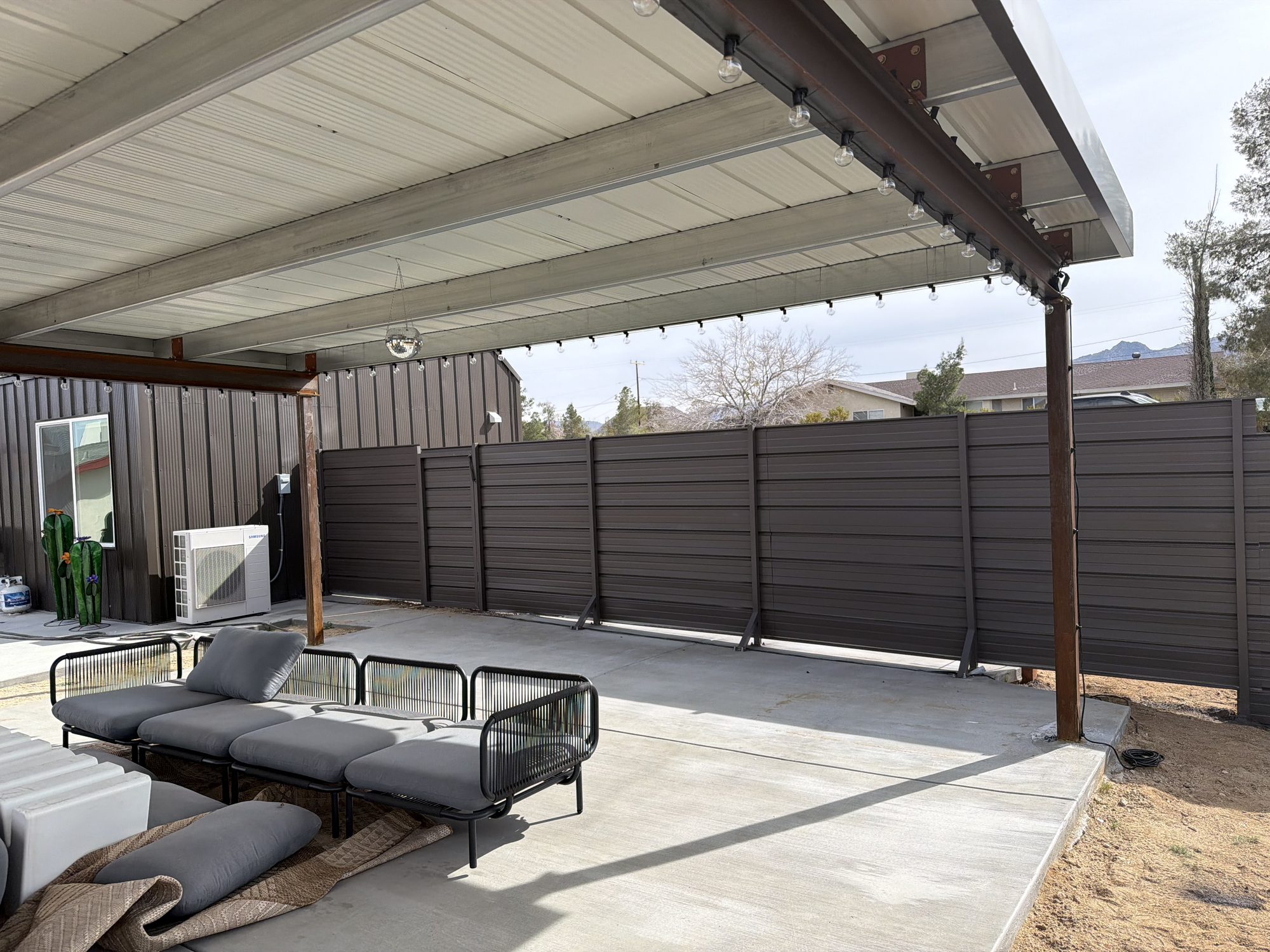 Covered patio with louvered privacy fence and lounge furniture