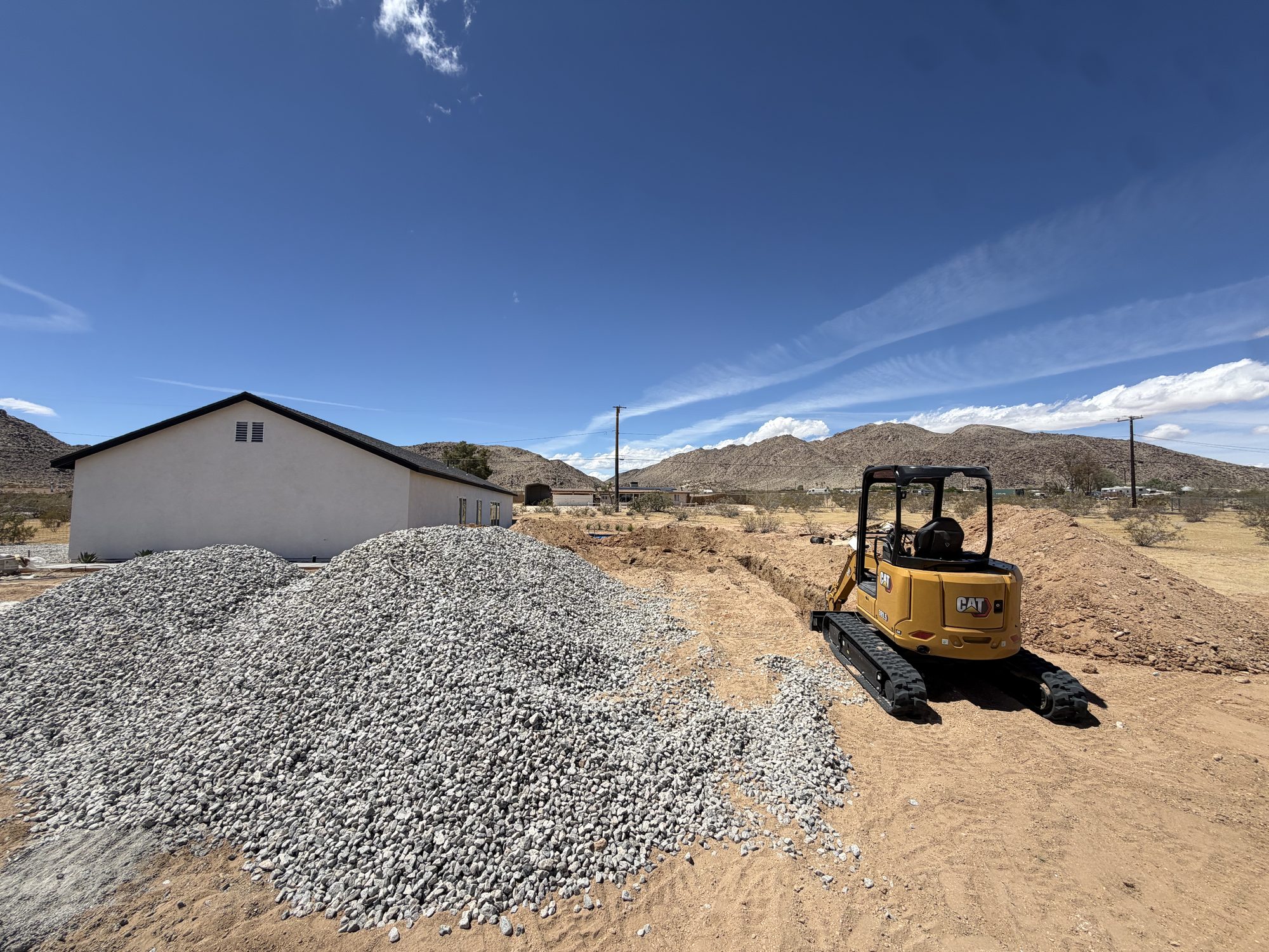 Mini excavator and gravel stockpile on a High Desert job site